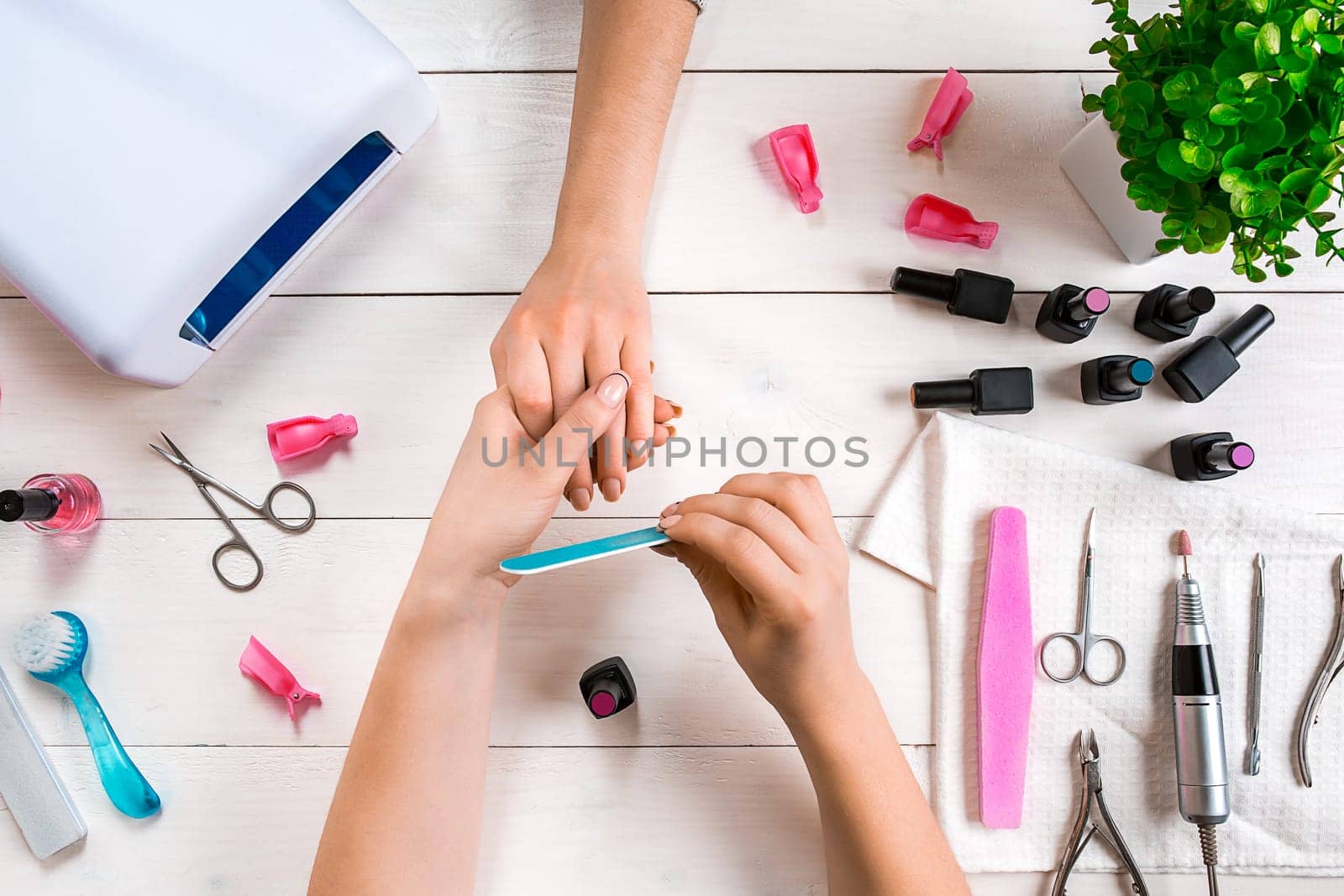 Manicure for the client. Close-up of the hands of a manicurist and client on a wooden background. Nail care. Manicure set and nail polish.