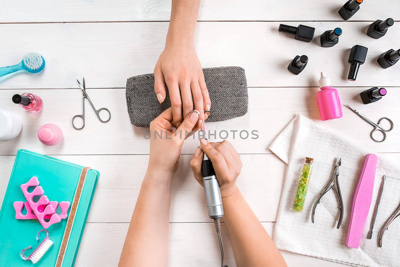Manicure for the client. Close-up of the hands of a manicurist and client on a wooden background. Nail care. Manicure set and nail polish.