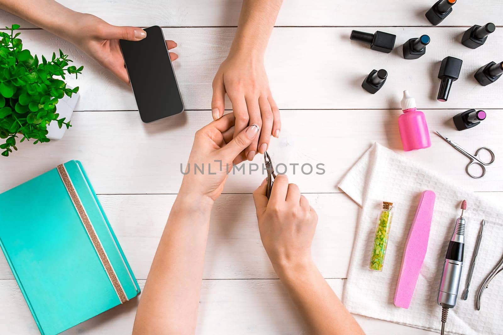 Manicure for the client. Close-up of the hands of a manicurist and client on a wooden background. Nail care. Manicure set and nail polish.