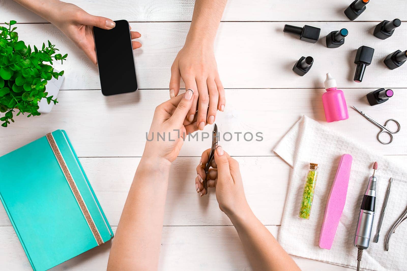 Manicure for the client. Close-up of the hands of a manicurist and client on a wooden background. Nail care. Manicure set and nail polish.