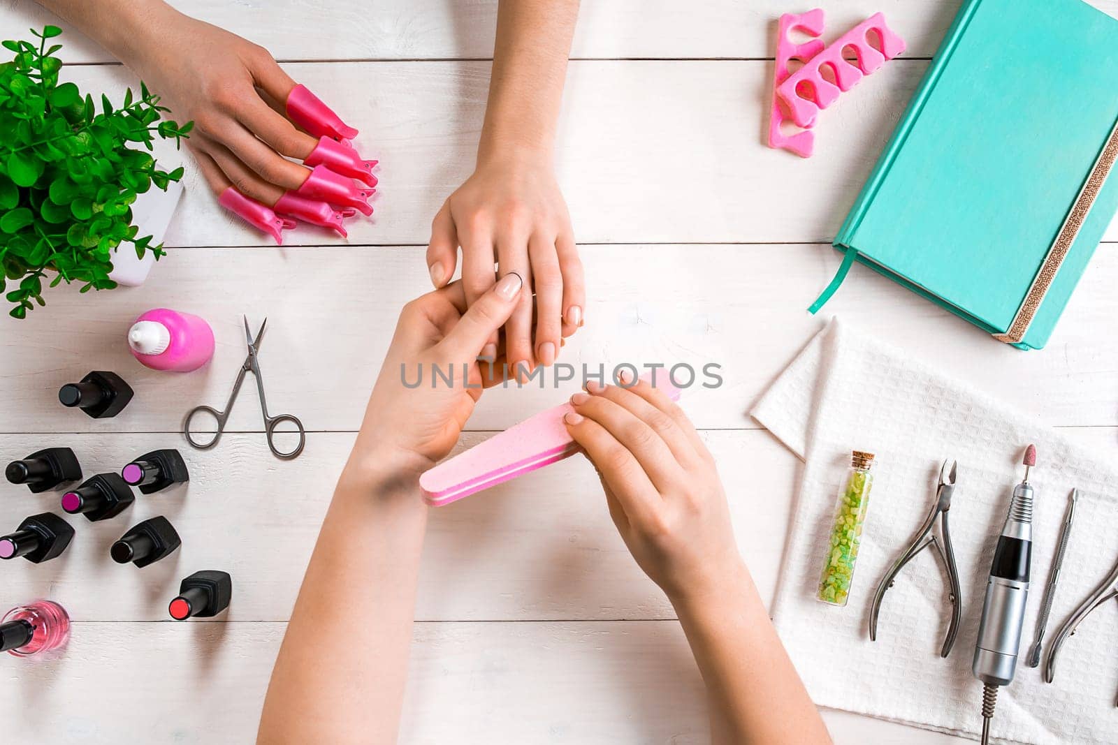 Manicure for the client. Close-up of the hands of a manicurist and client on a wooden background. Nail care. Manicure set and nail polish.