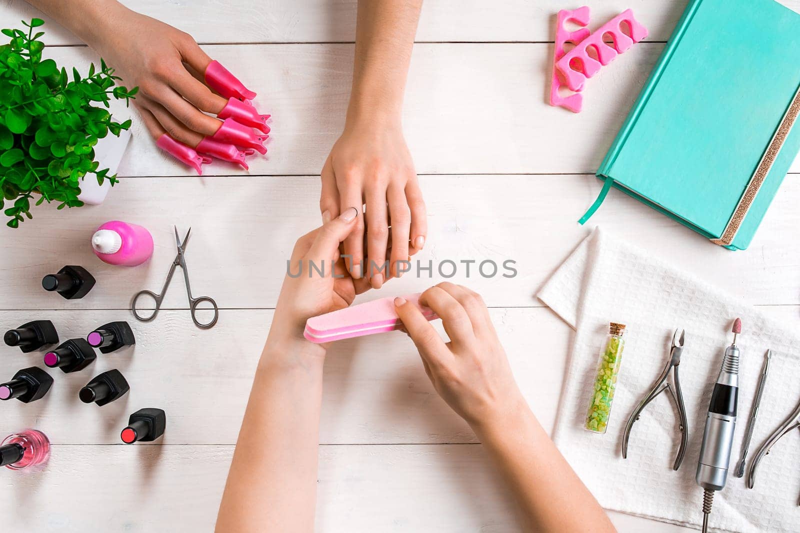 Manicure for the client. Close-up of the hands of a manicurist and client on a wooden background. Nail care. Manicure set and nail polish.