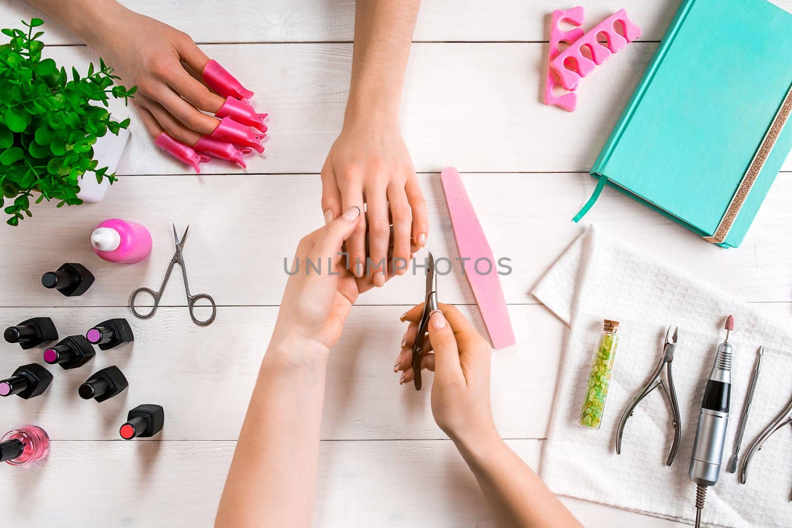 Manicure for the client. Close-up of the hands of a manicurist and client on a wooden background. Nail care. Manicure set and nail polish.