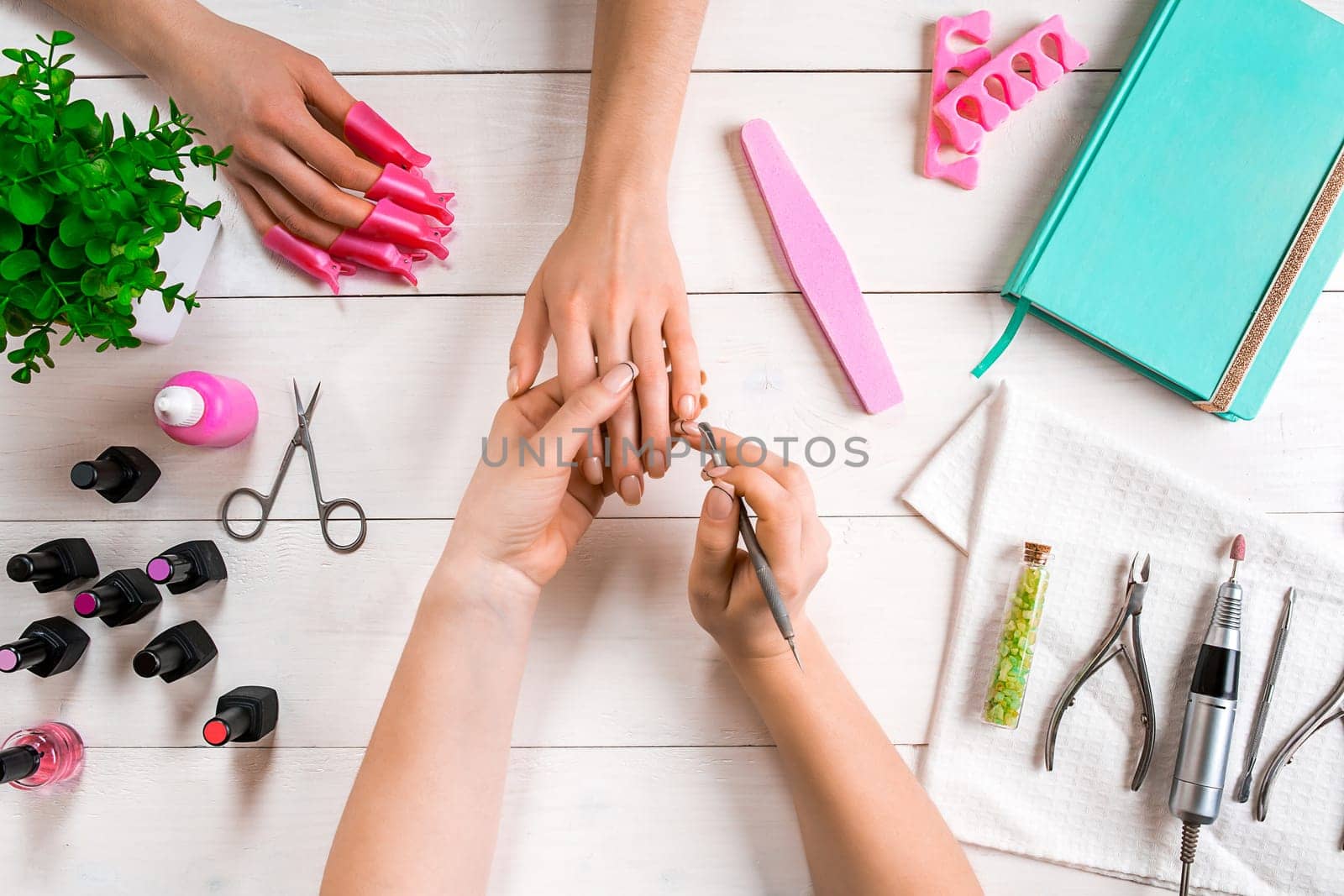 Manicure for the client. Close-up of the hands of a manicurist and client on a wooden background. Nail care. Manicure set and nail polish.