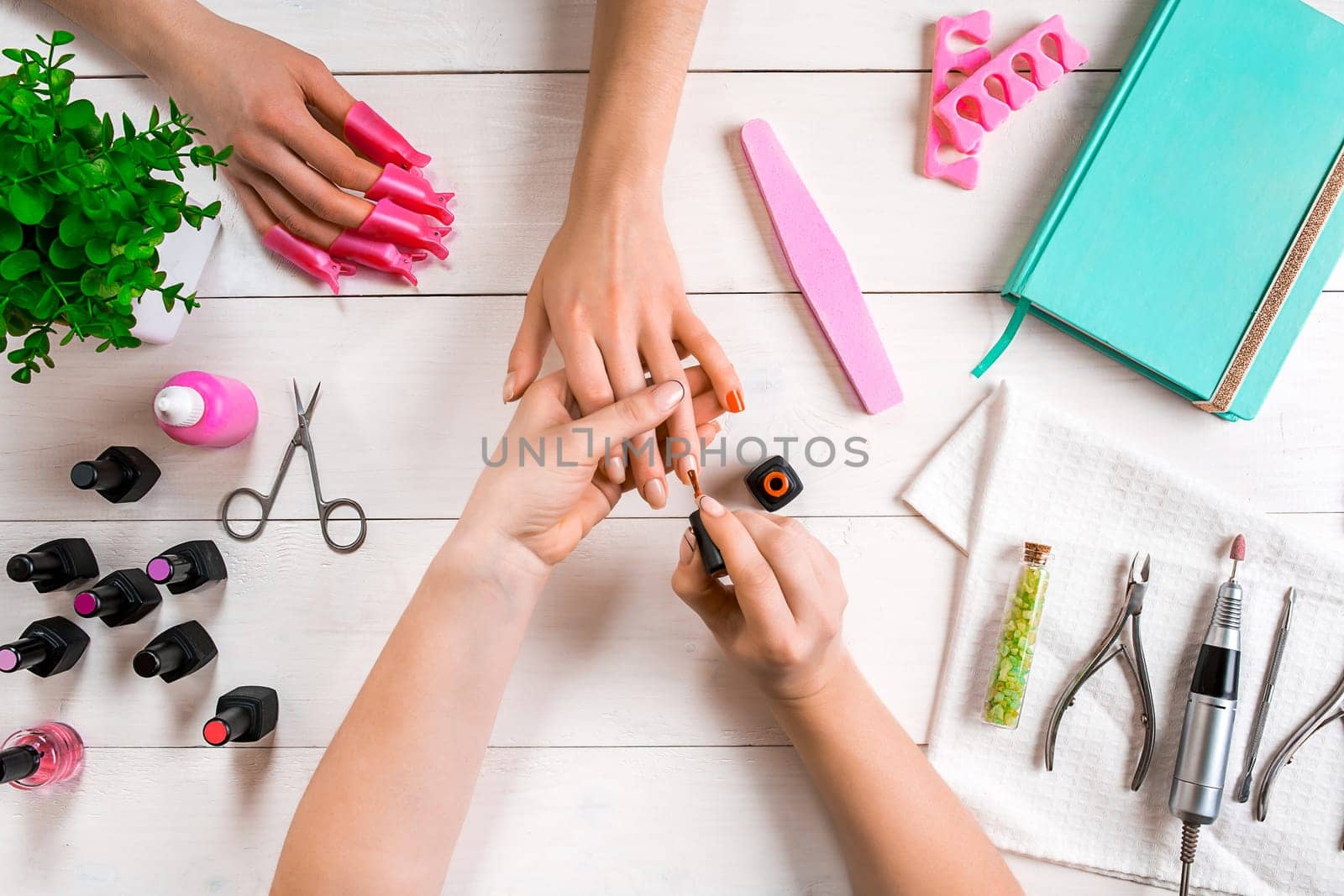 Manicure for the client. Close-up of the hands of a manicurist and client on a wooden background. Nail care. Manicure set and nail polish.