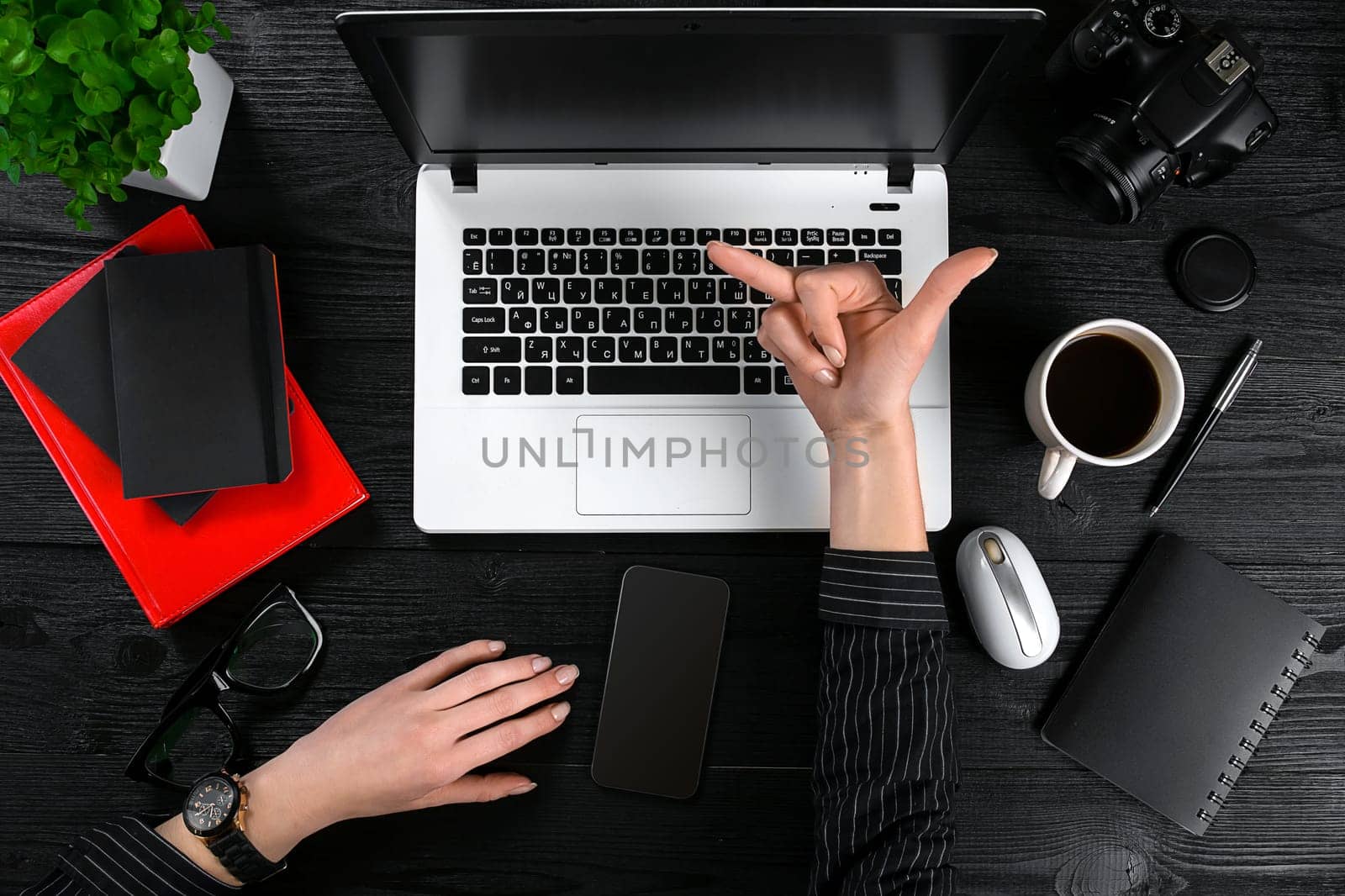 Business and technology topic: the hand of woman in a black shirt showing gesture against a black and white background laptop at the desk. Top view