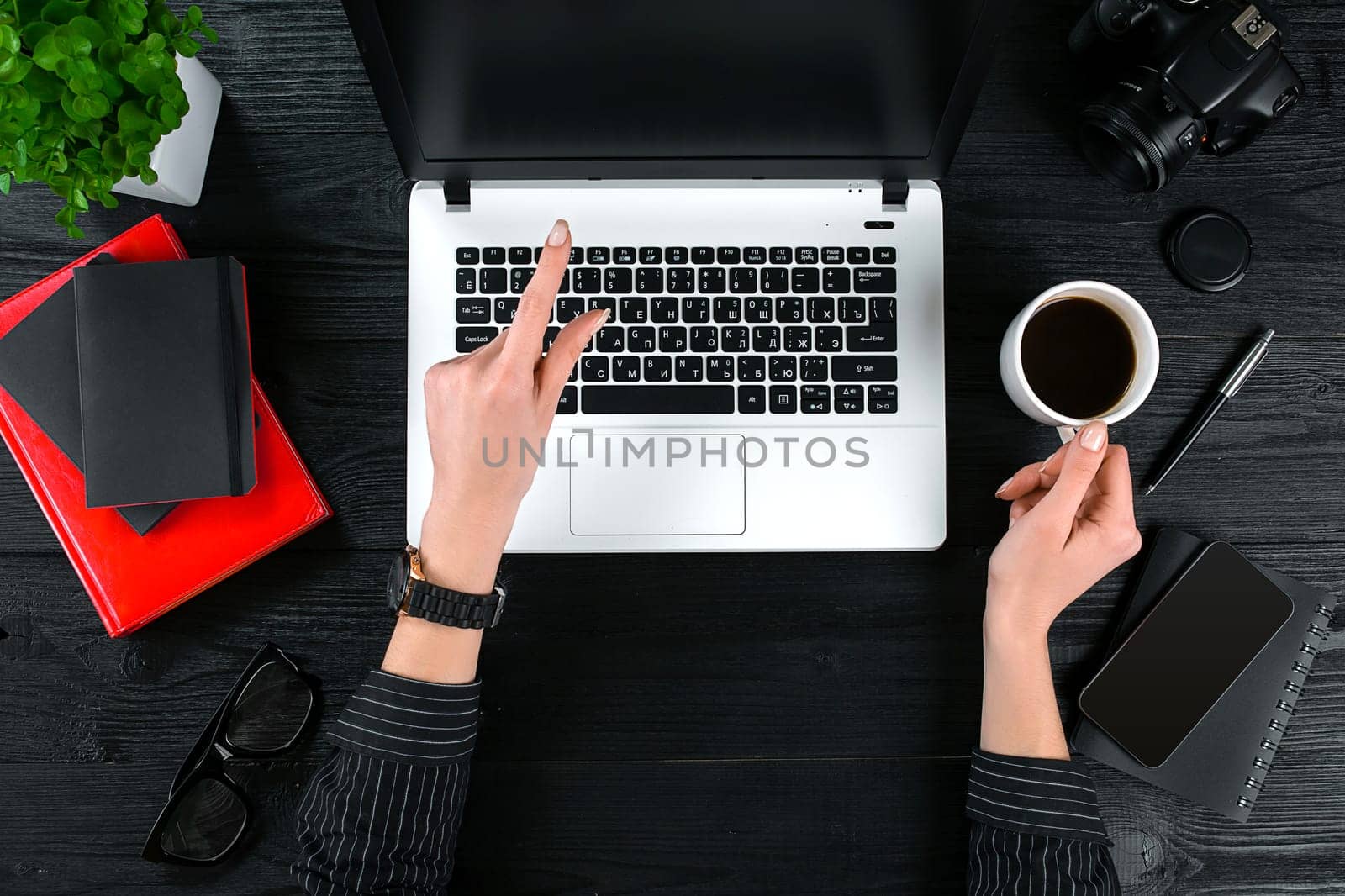 Business and technology topic: the hand of woman in a black shirt showing gesture against a black and white background laptop at the desk. Top view
