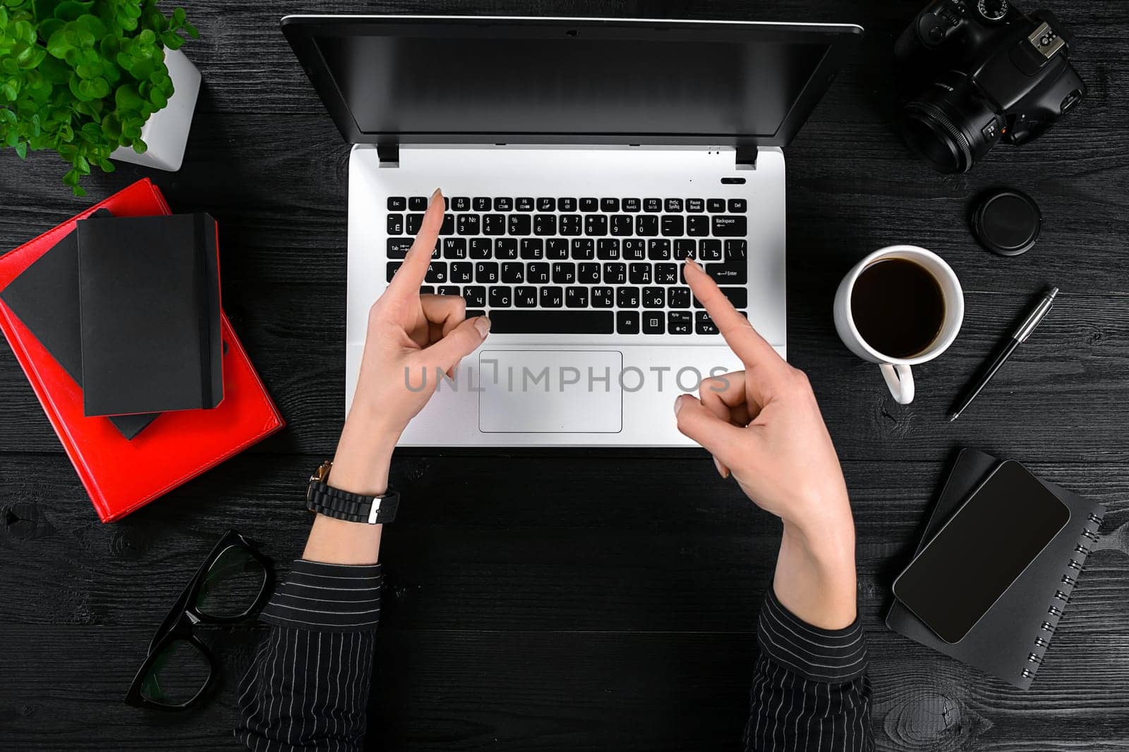 Business and technology topic: the hand of woman in a black shirt showing gesture against a black and white background laptop at the desk. Top view