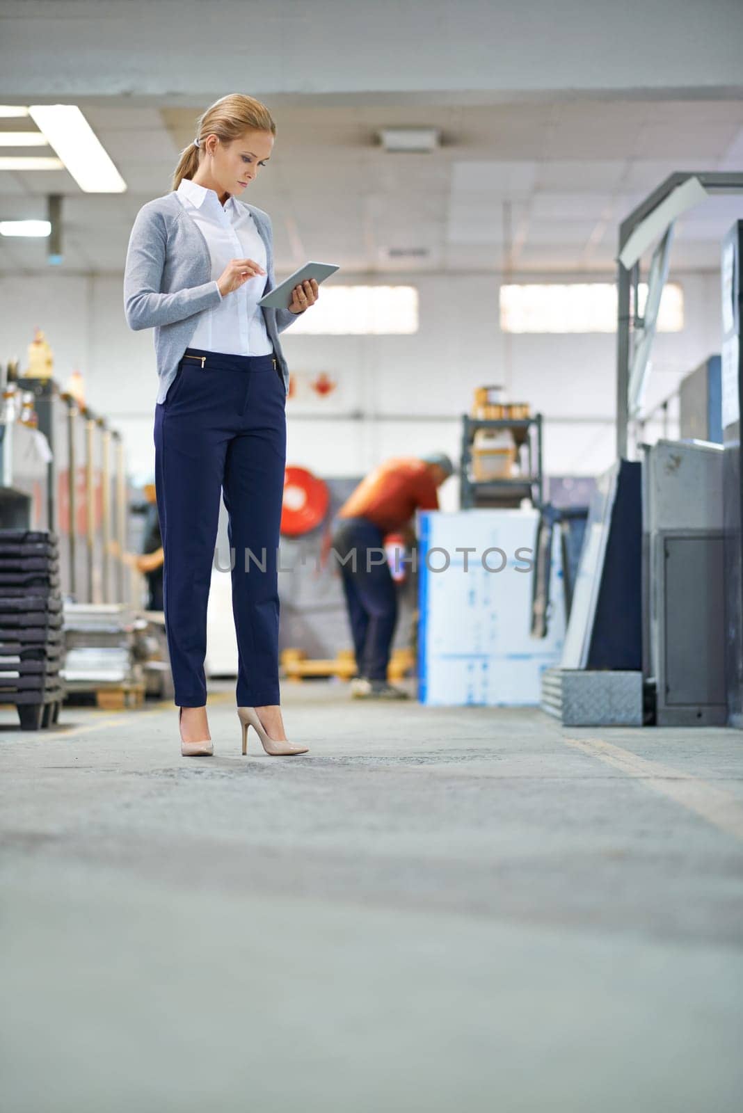 Assessing their productivity levels. A manager on the factory floor monitoring productivity with her digital tablet. by YuriArcurs