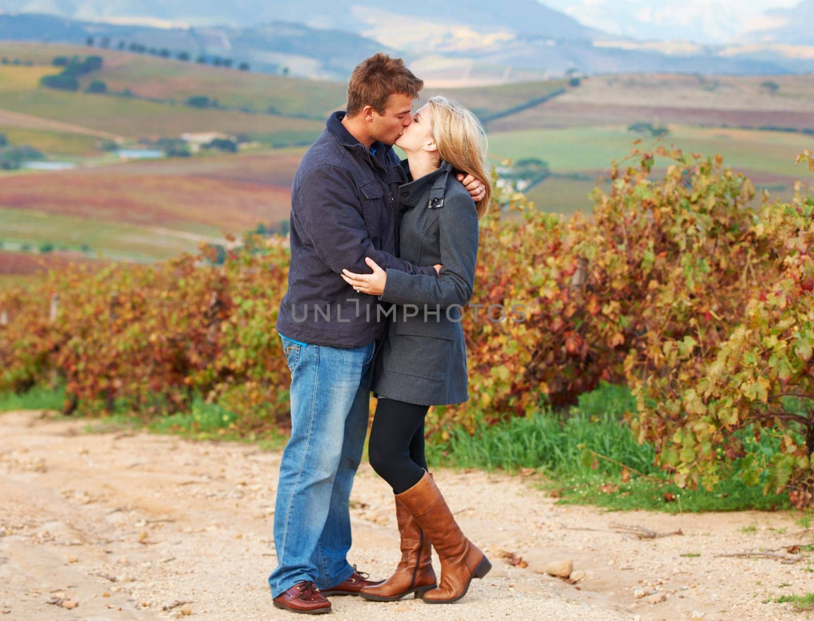 Love, romance and couple kissing in a vineyard outdoor while on a date in celebration of their relationship. Romantic, dating or kiss with a man and woman on a farm for agriculture or sustainability by YuriArcurs