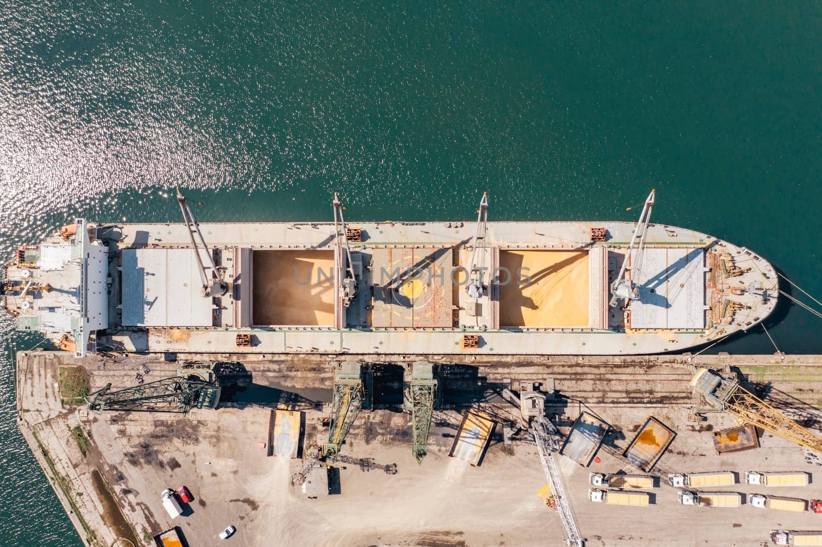 Aerial Top down view Black Sea port Loading of dry cargo ship with ukranian grain by cranes. Maritime grain Import and export concept