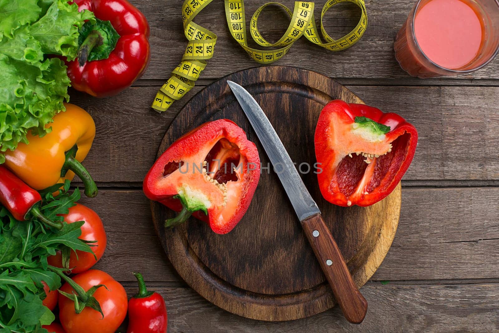 Glass of tomato juice with vegetables and measuring tape on wooden table close-up. On the cutting board is sliced pepper. Copy space. Top view