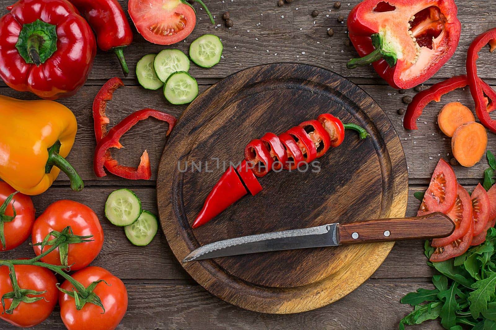 Cut pepper on a wooden board and vegetables on a table. Copy space. Top view