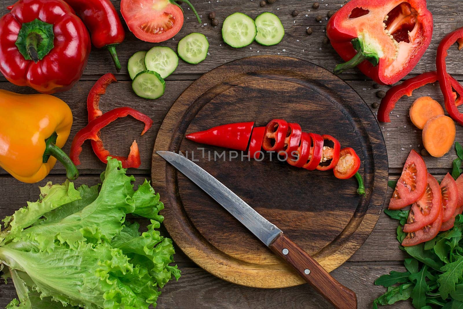 Cut pepper on a wooden board and vegetables on a table. Copy space. Top view