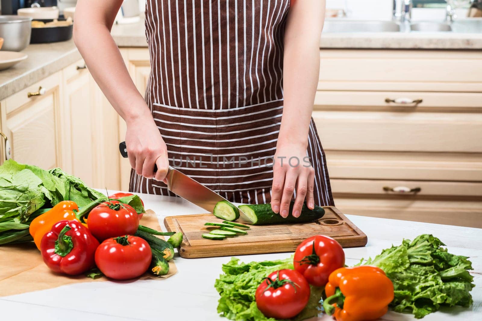 Young woman cooking in the kitchen at home. Healthy food. Diet. Dieting concept. Healthy lifestyle. Cooking at home. Prepare food. A woman cuts a cucumber and vegetables with a knife.
