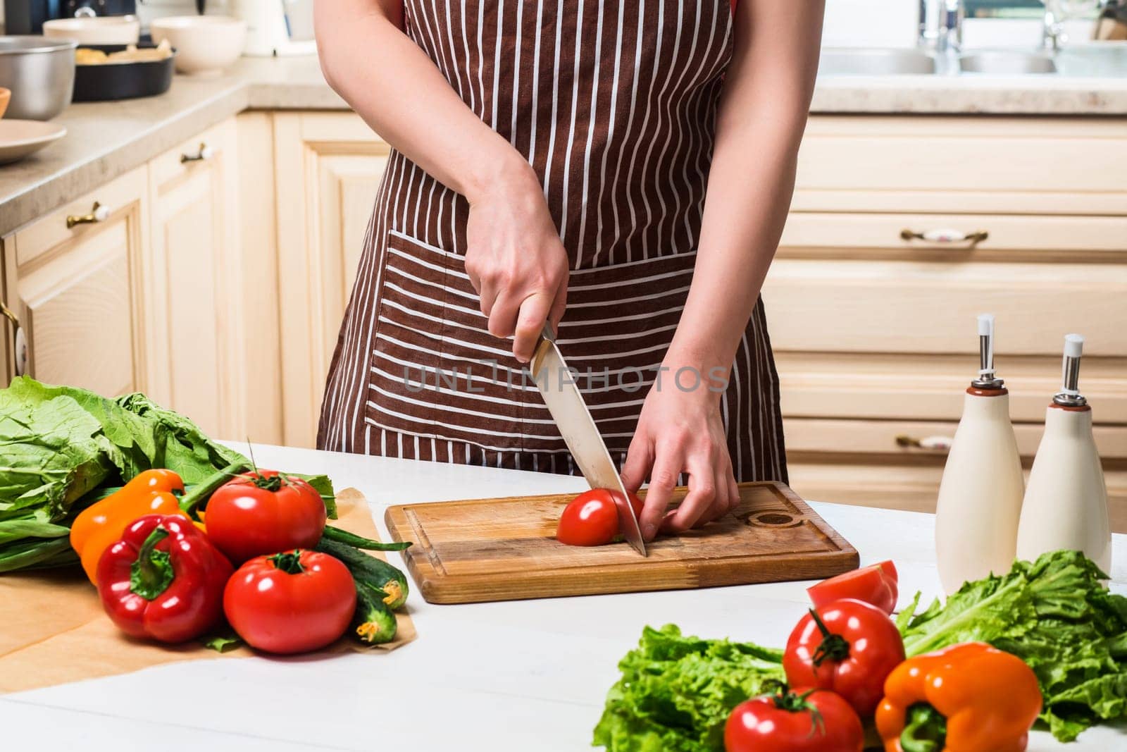 Young woman cooking in the kitchen at home. Healthy food. Diet. Dieting concept. Healthy lifestyle. Cooking at home. Prepare food. A woman cuts a tomato and vegetables with a knife.