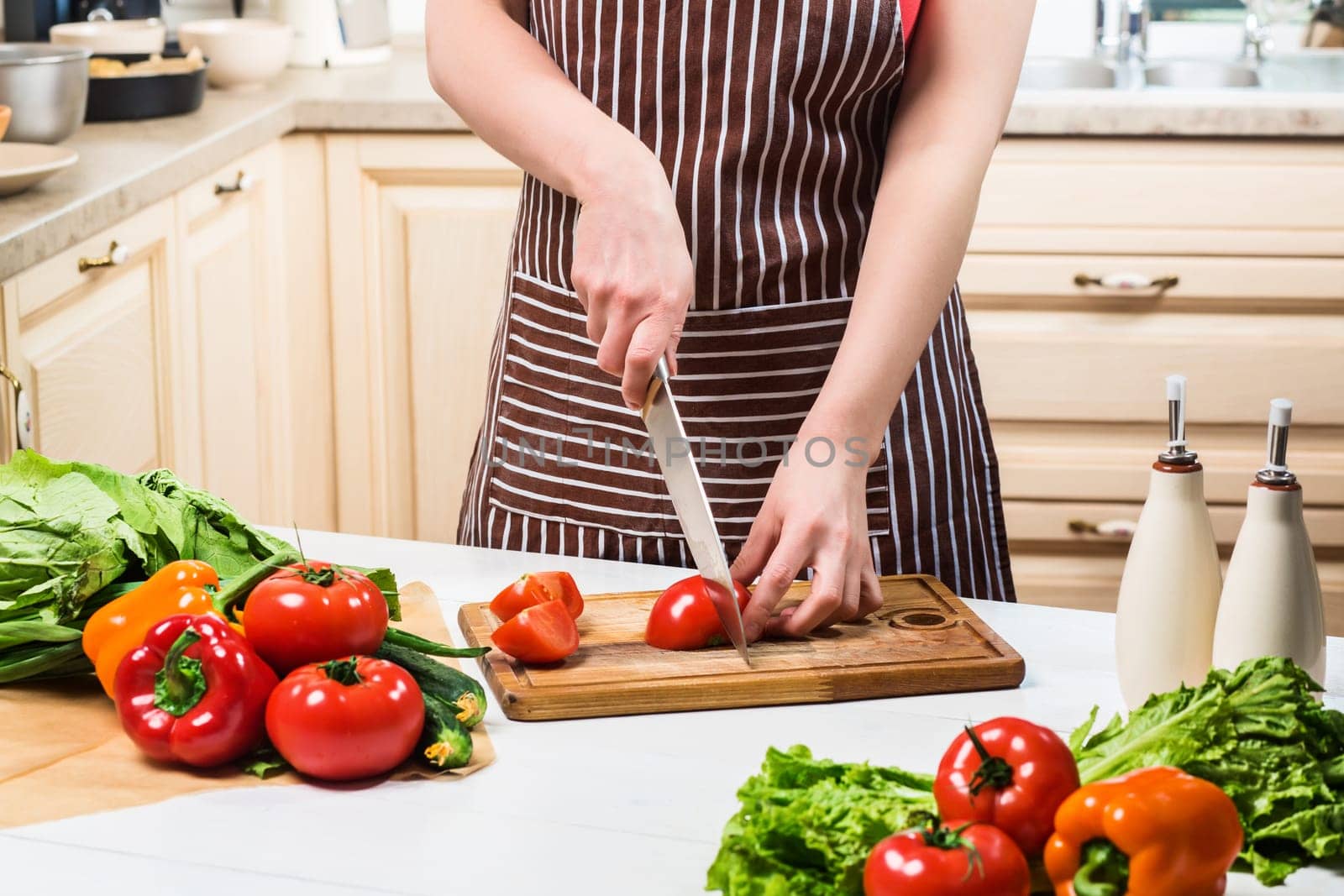 Young woman cooking in the kitchen at home. Healthy food. Diet. Dieting concept. Healthy lifestyle. Cooking at home. Prepare food. A woman cuts a tomato and vegetables with a knife.