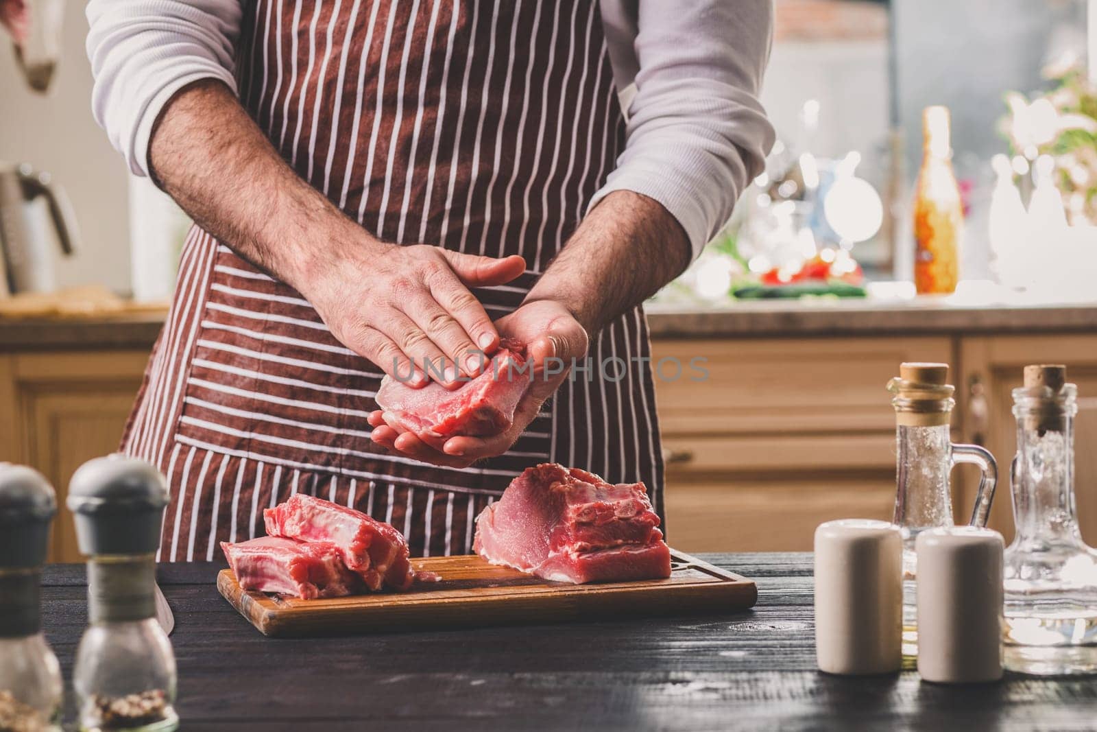 Preparation of dinner. Cooking, processing of meat beef, tenderloin . Person man's hands marinates meat - sprinkles with salt, pepper. Black wooden table, spices and herbs in the frame.