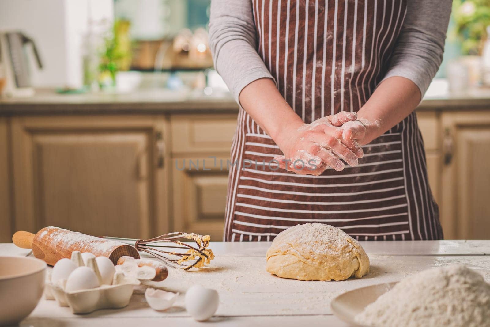 Woman slap his hands above dough closeup. Baker finishing his bakery, shake flour from his hands, free space for text. Homemade bakery, cooking process concept