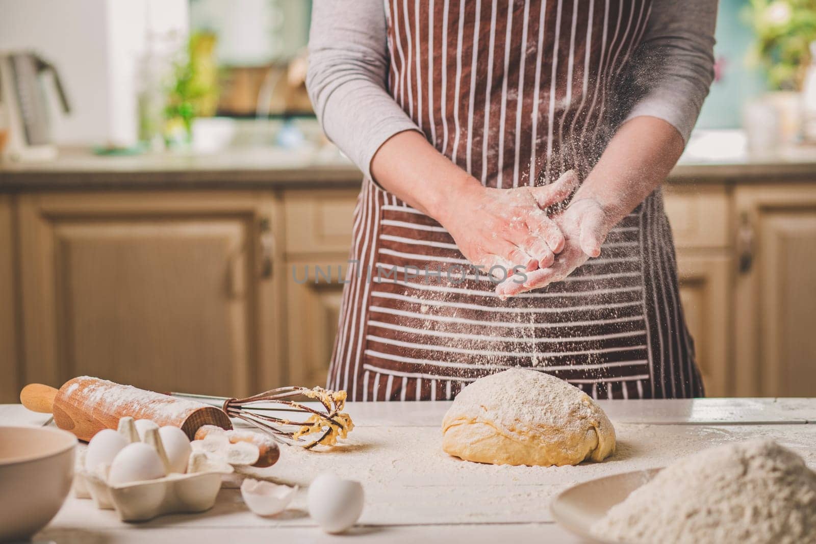 Woman slap his hands above dough closeup. Baker finishing his bakery, shake flour from his hands, free space for text. Homemade bakery, cooking process concept