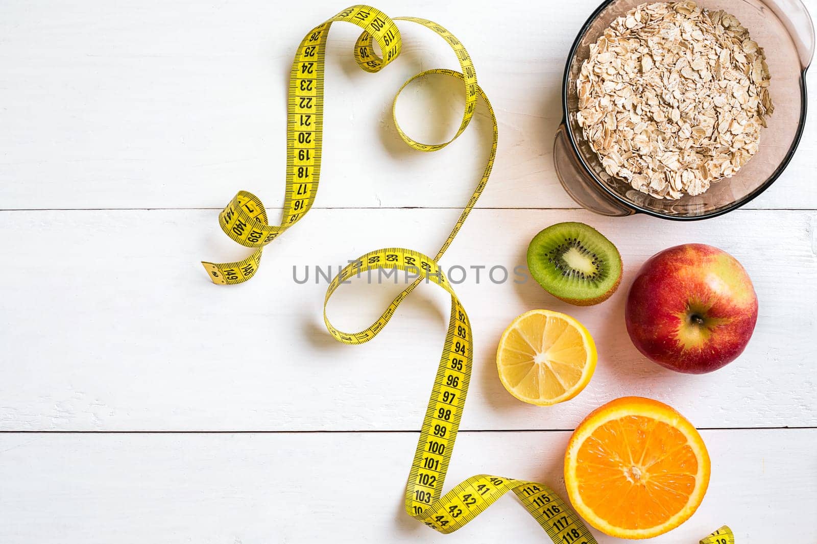 Fitness concept with fruit, bowl of oatmeal and centimeter. Top view background concept. Copy space