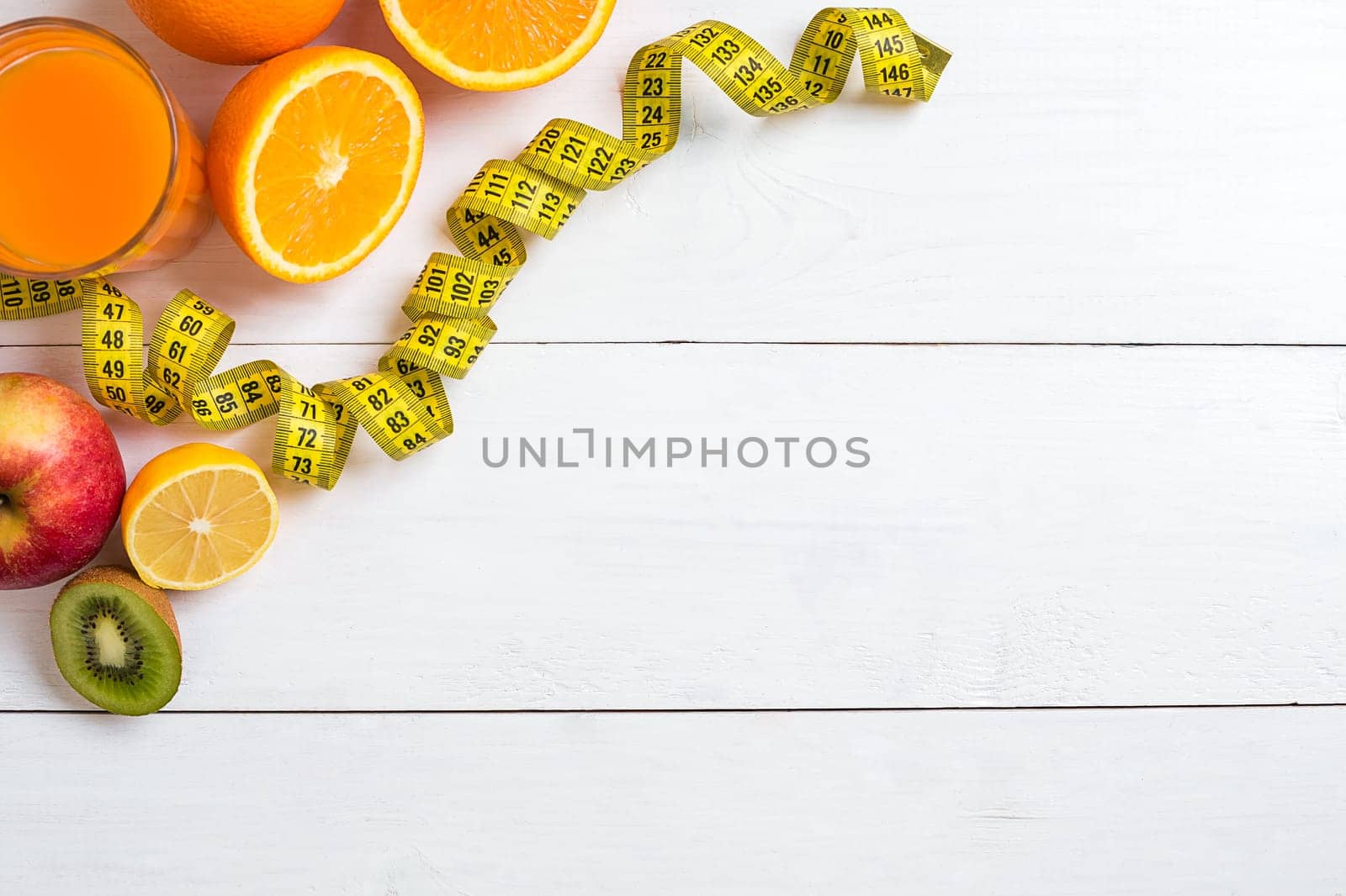 Fresh fruits with tape measure over white wooden background. Fitness concept. Top view. Copy space Flat lay
