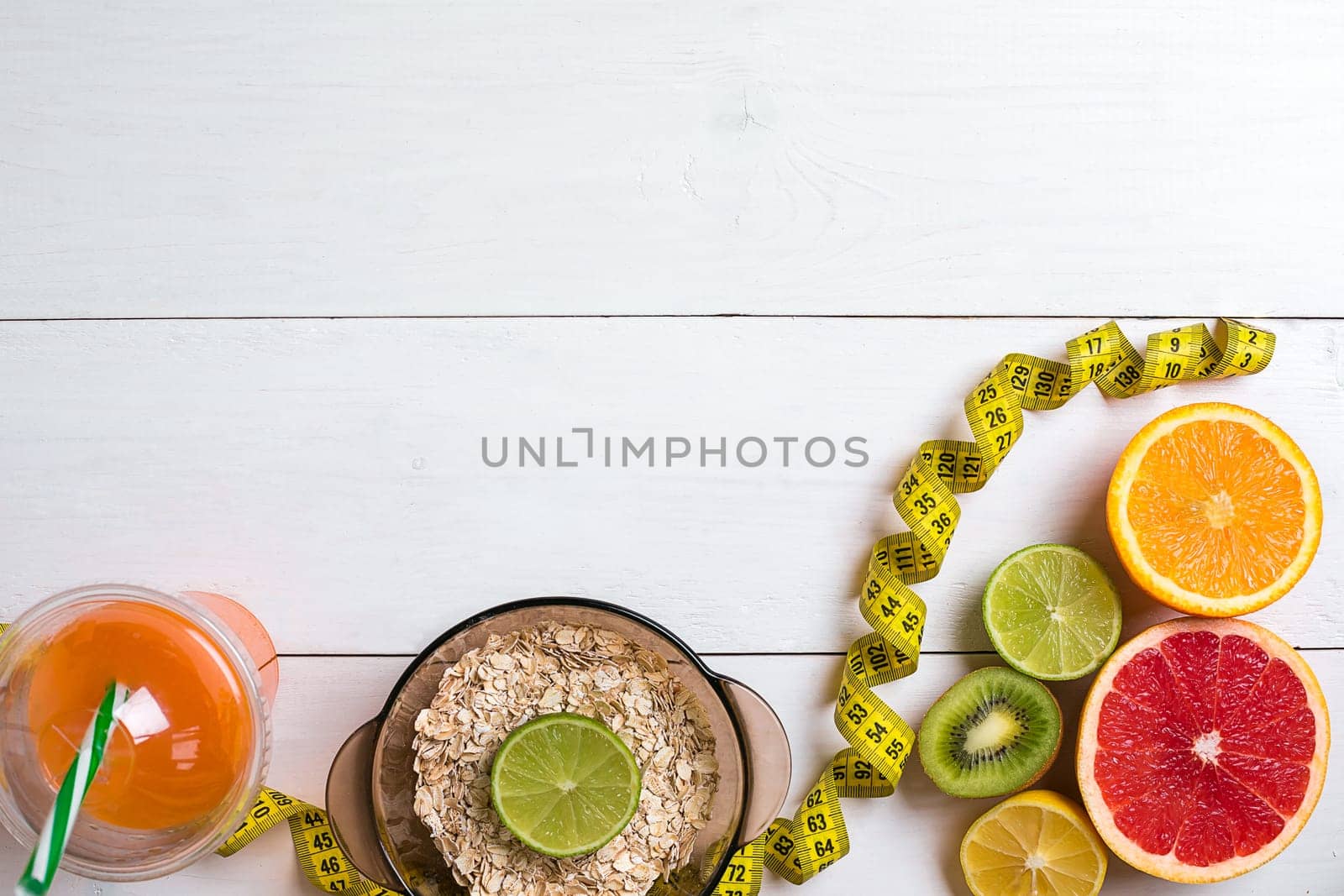 Fresh fruits with tape measure over white wooden background. Fitness concept. Flat lay. Top view. Copy space
