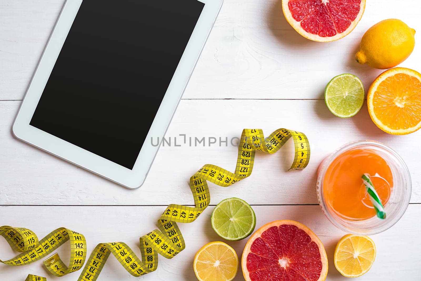 Fitness concept with fruit, bowl of oatmeal and centimeter. Top view background concept. Copy space. Tablet with a black screen