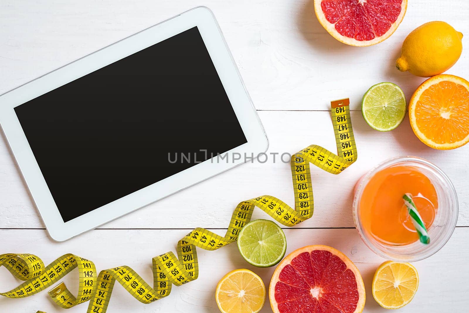 Fitness concept with fruit, bowl of oatmeal and centimeter. Top view background concept. Copy space. Tablet with a black screen