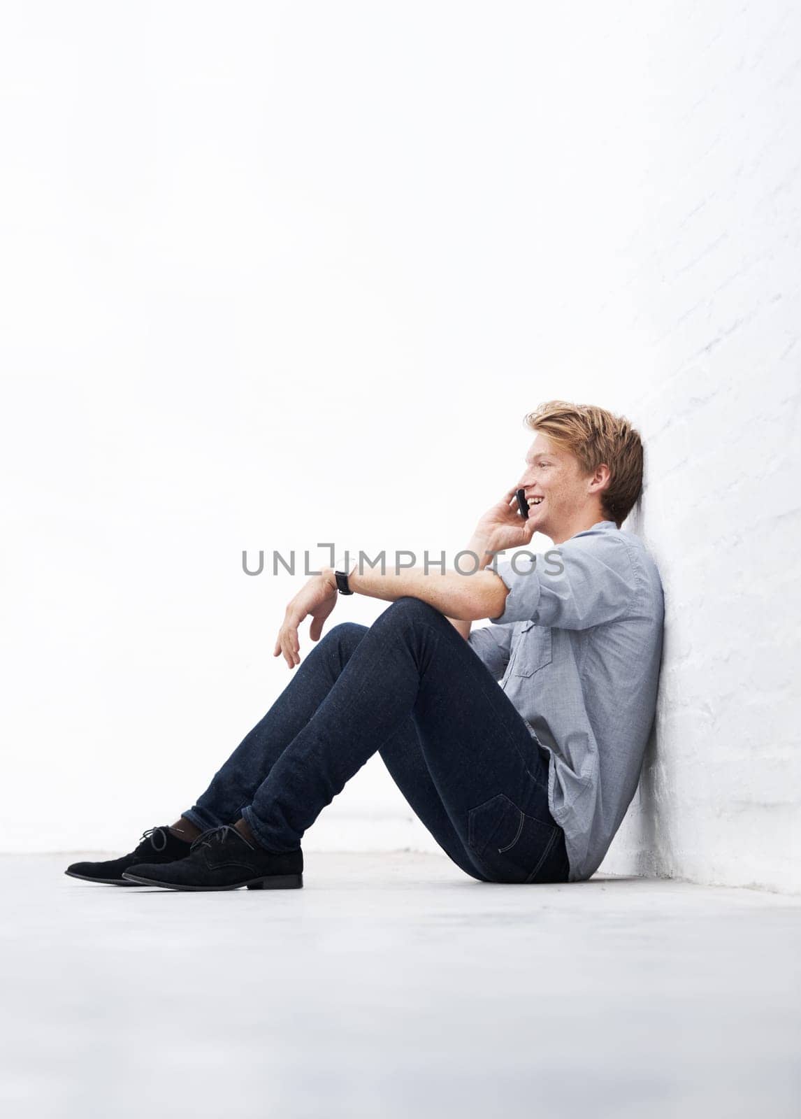 Man, phone call and floor with space by wall with smile, communication and talk at startup. Young businessman, entrepreneur and sitting for conversation on smartphone with mockup at small business by YuriArcurs