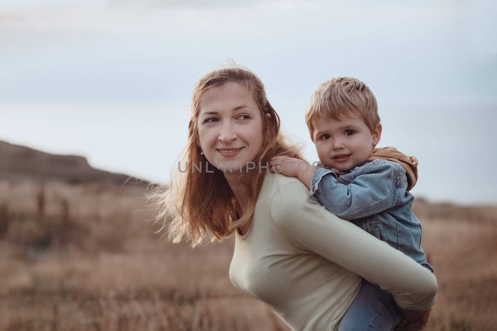 Mother with little son in summer in the field at a sunset