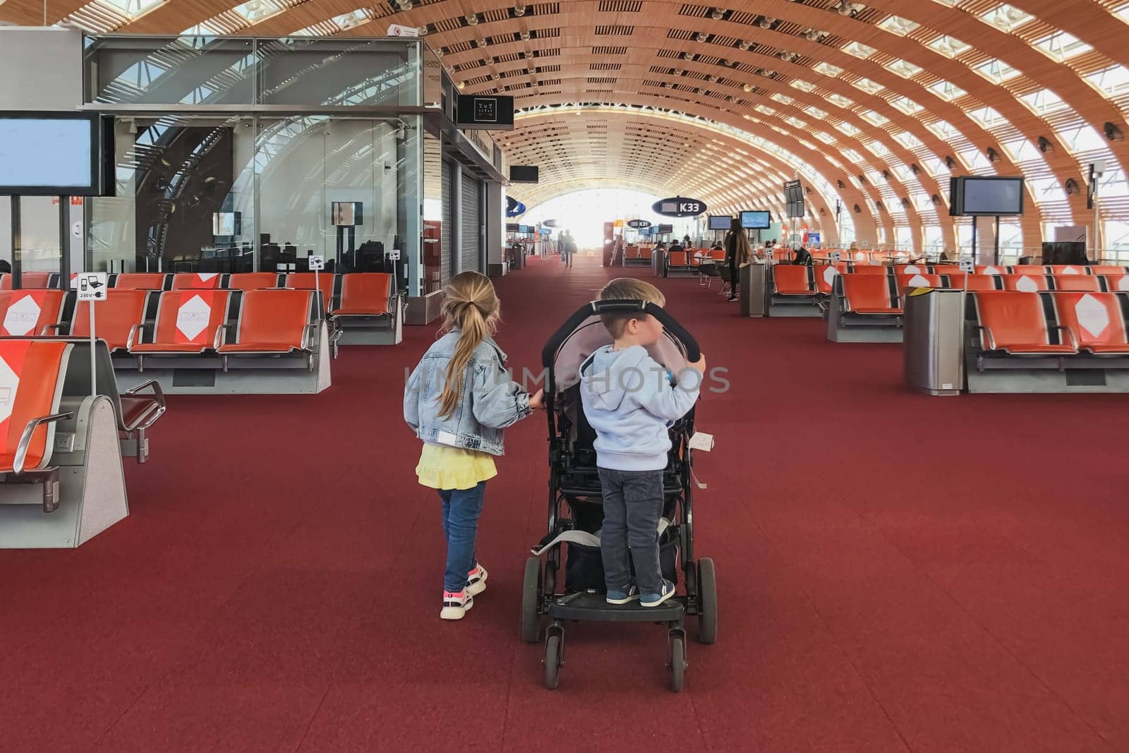 The kids near the stroller in the waiting room at the airport