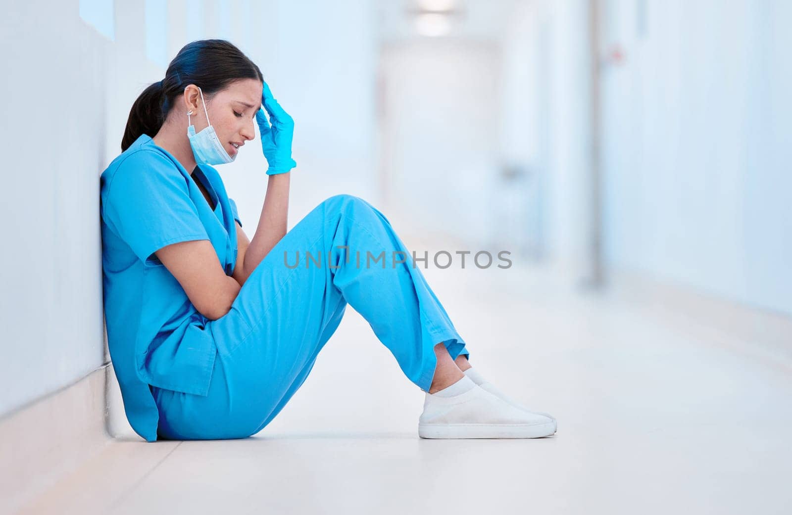 Everyone needs to cry. a young female nurse sitting on the floor looking depressed. by YuriArcurs