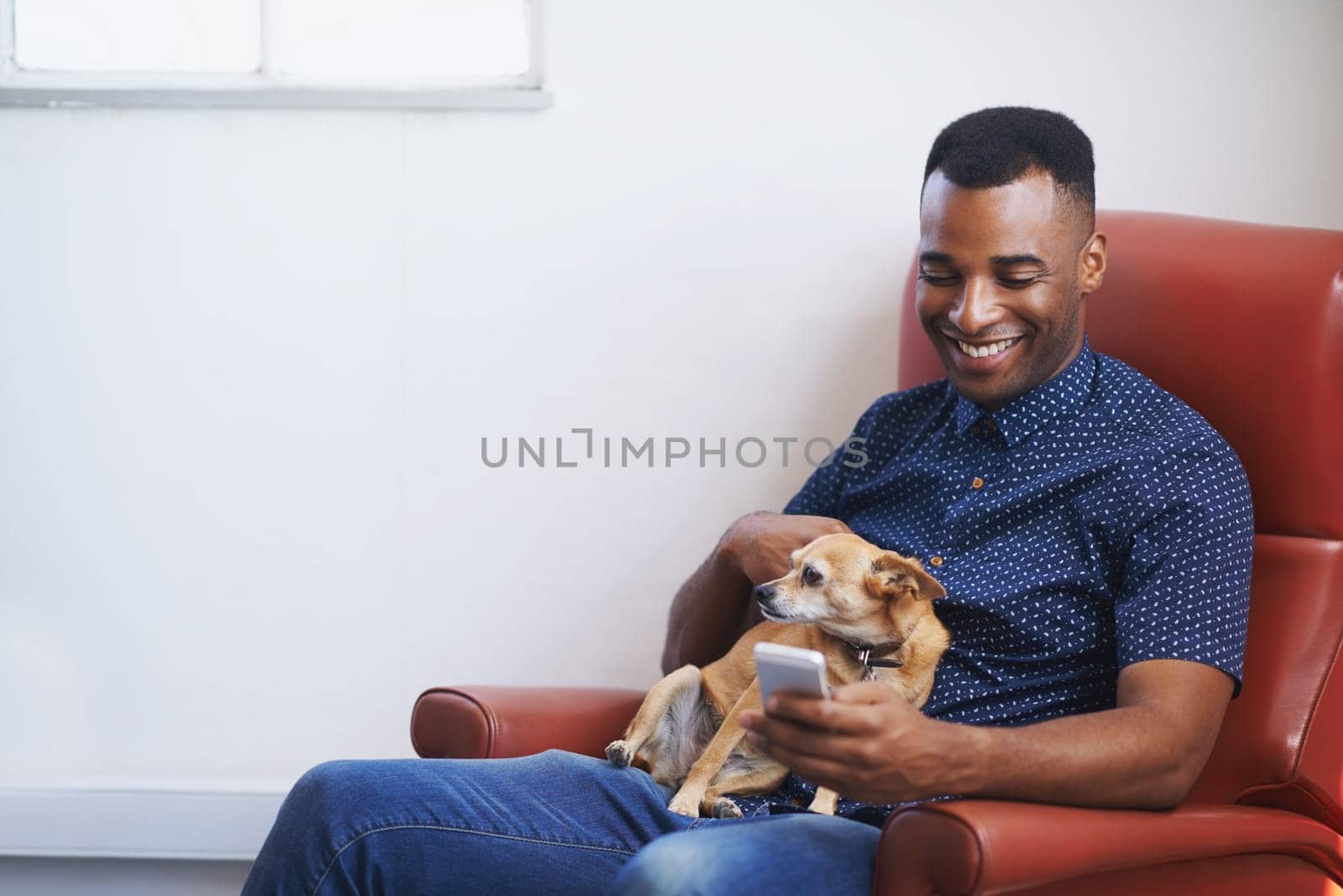 Communication and companionship. A handsome young man using his cellphone with his dog on his lap