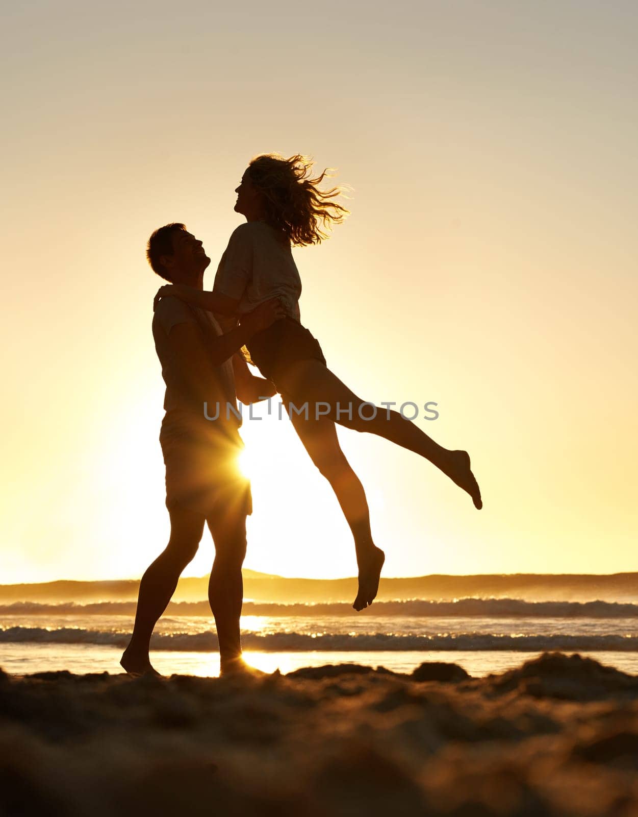 Partners in everything. a romantic couple having fun on the beach at sunset. by YuriArcurs