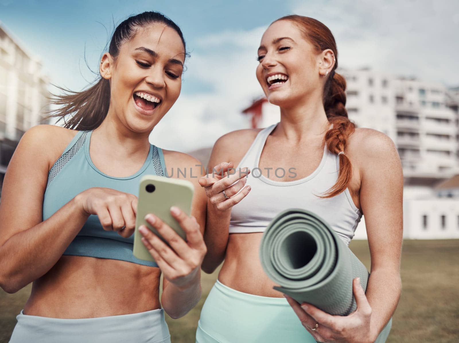 Yoga, fitness and phone with woman friends laughing at a meme in the park together during exercise. Pilates, social media and training with a female and friend joking outside on a field for a workout by YuriArcurs