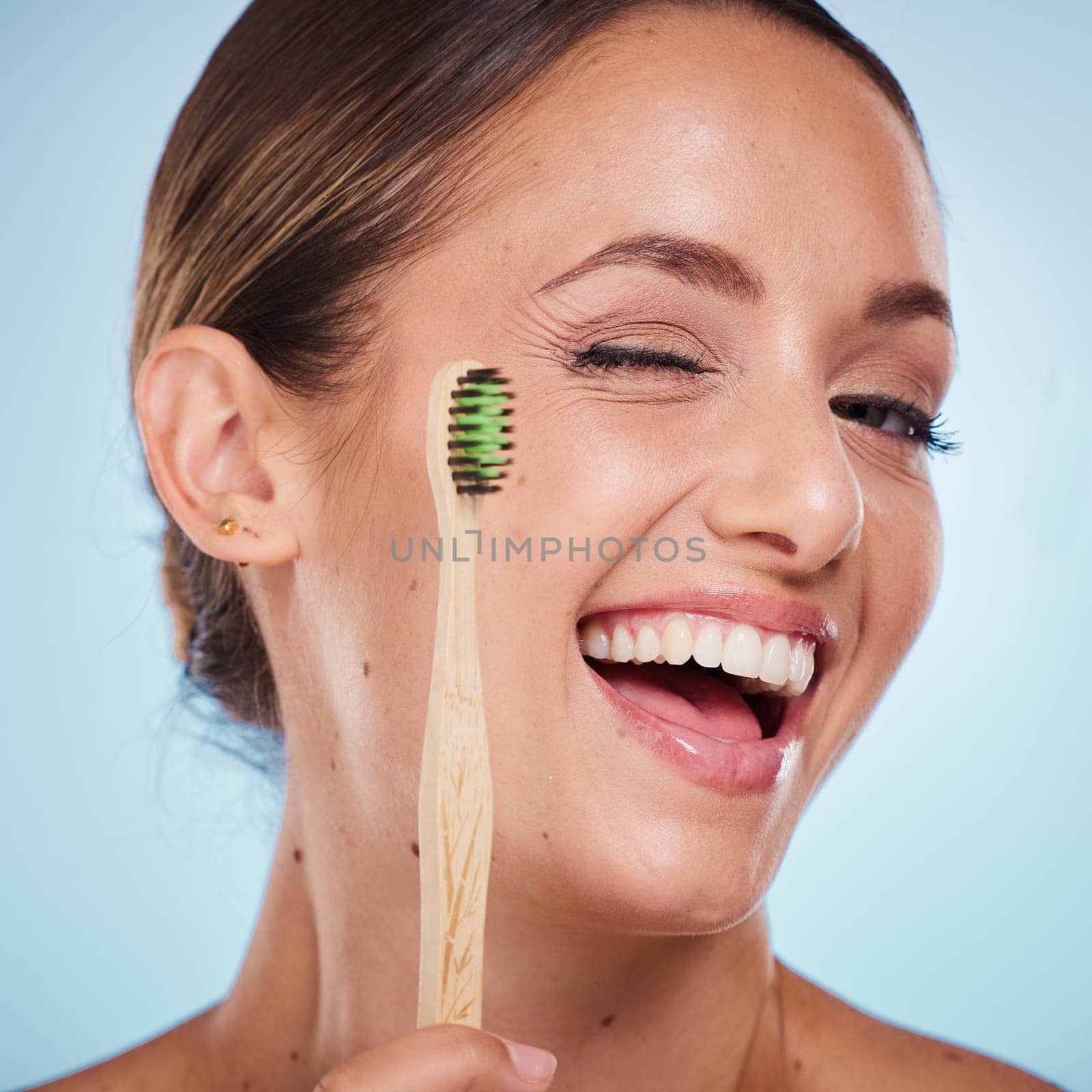 Brushing teeth, dental and woman with toothbrush, wink and beauty, oral health and fresh breath with studio background. Mouth wellness, Invisalign portrait and teeth whitening with bamboo brush. by YuriArcurs