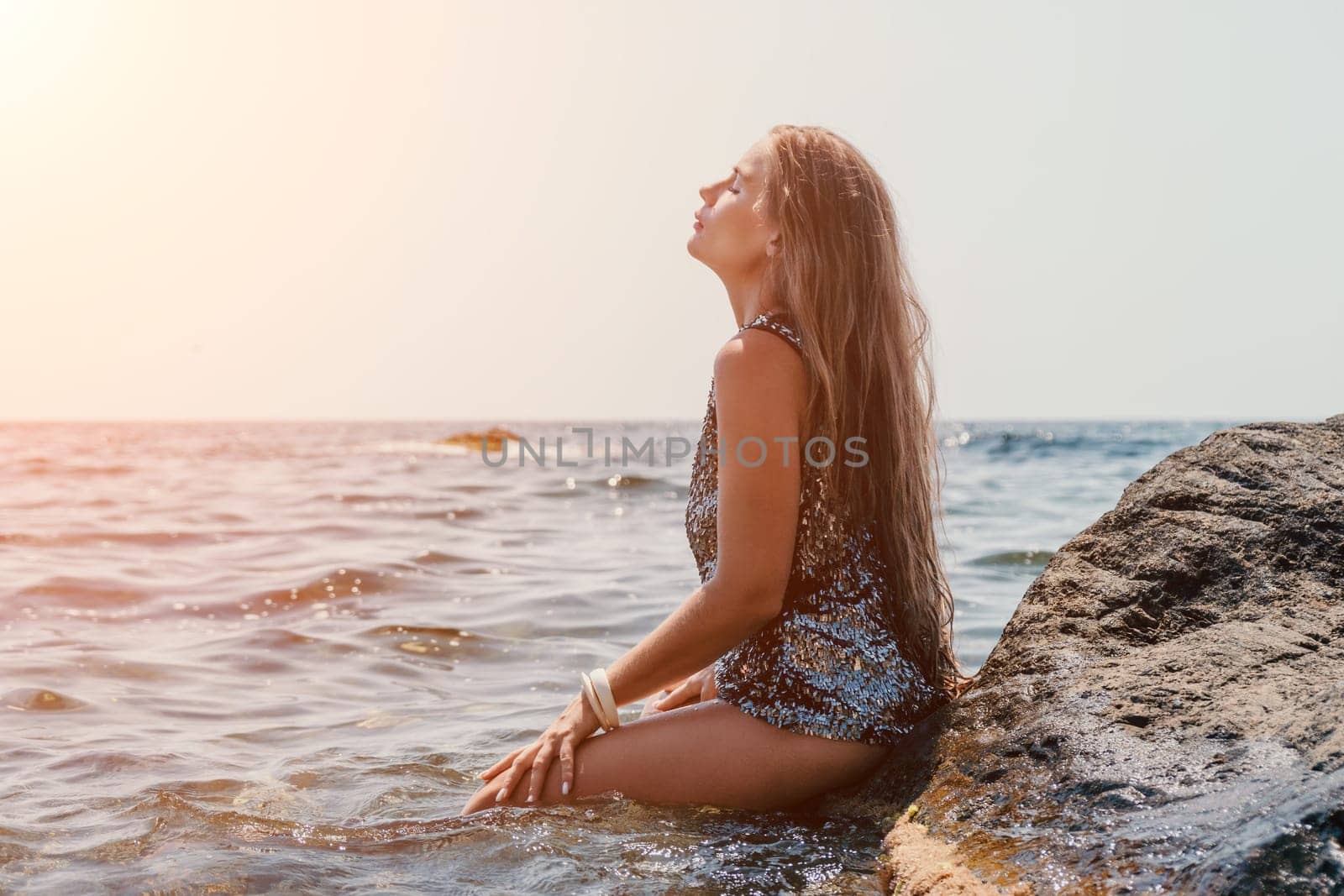 Woman travel sea. Young Happy woman in a long red dress posing on a beach near the sea on background of volcanic rocks, like in Iceland, sharing travel adventure journey