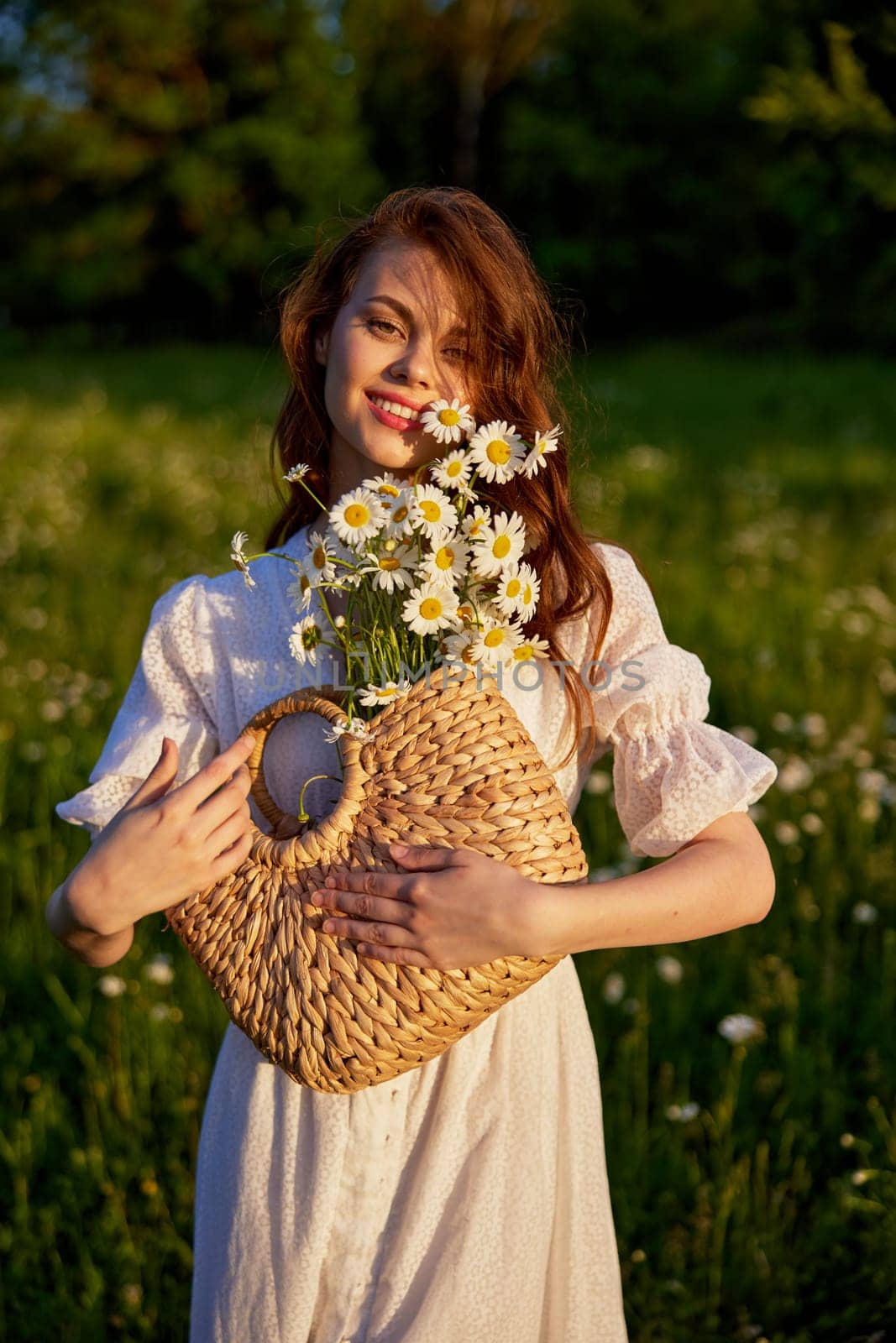 portrait of a beautiful, happy red-haired woman holding a basket of daisies in her hands. High quality photo