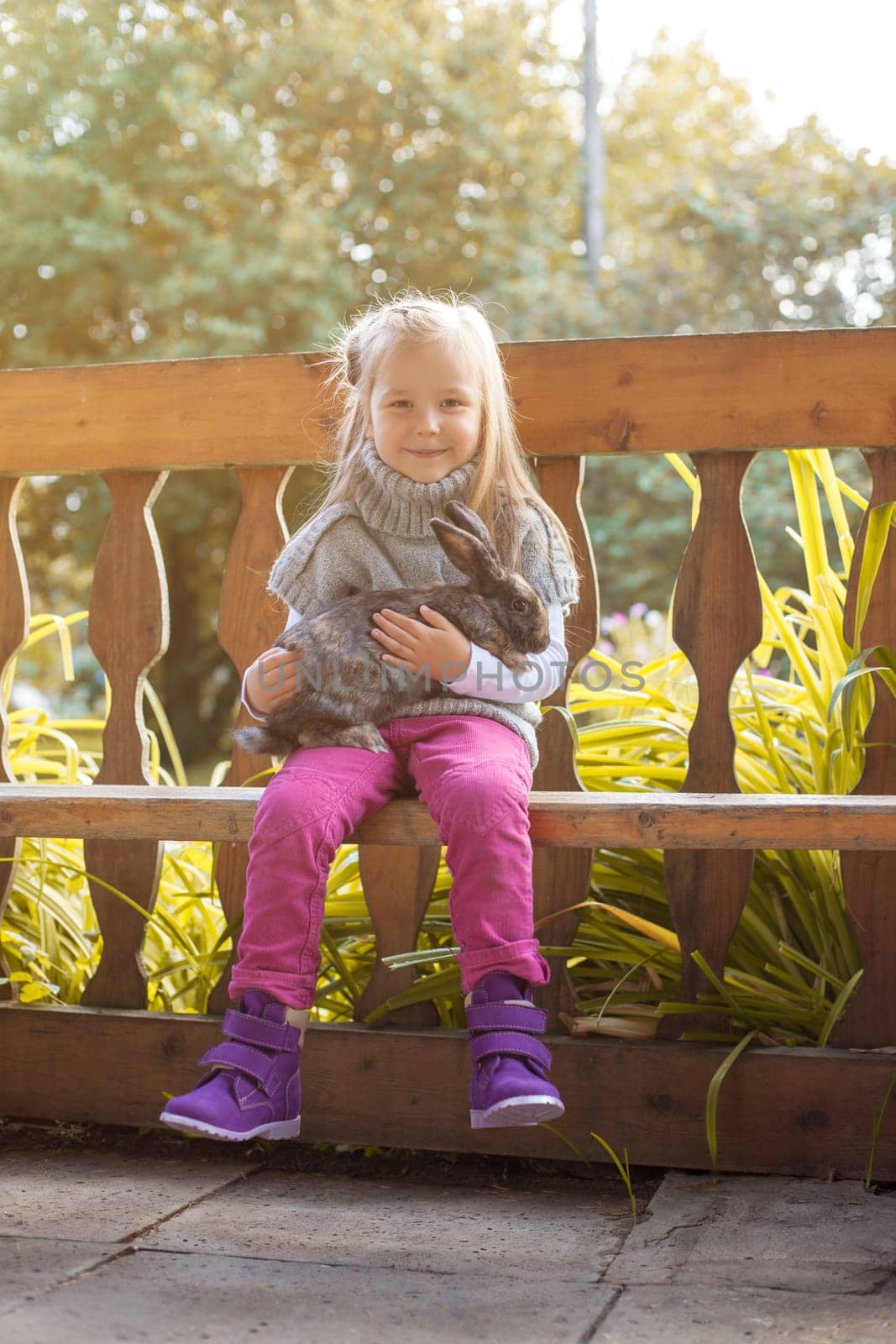 Smiling little girl posing in arbor with rabbit, close-up