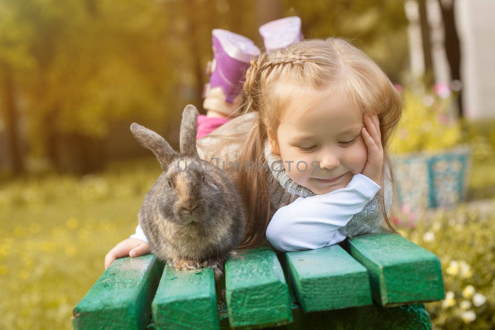 Adorable girl posing on bench with cute rabbit, close-up