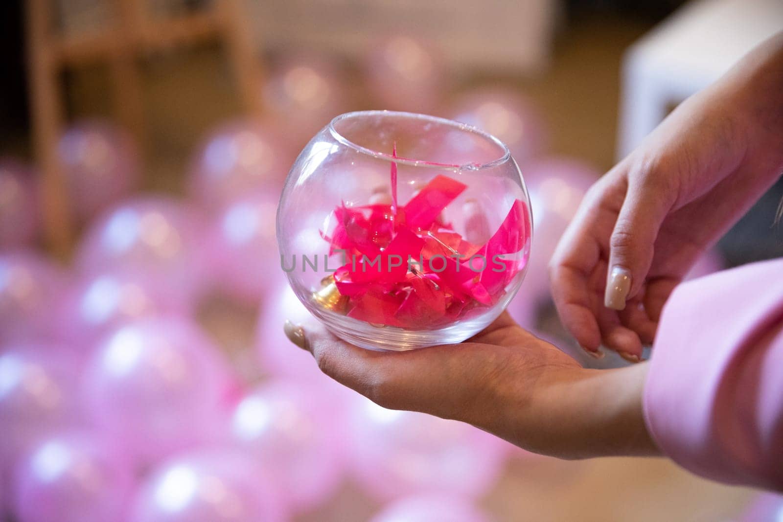 The pink-colored bows symbolize the breast cancer prevention movement for women and men. A woman holds a glass container in her hands.