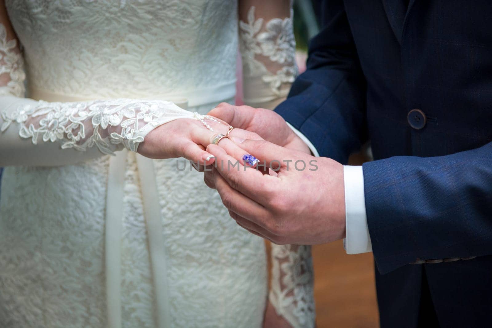 Newlyweds exchange rings, groom puts the ring on the bride's hand in marriage registry office