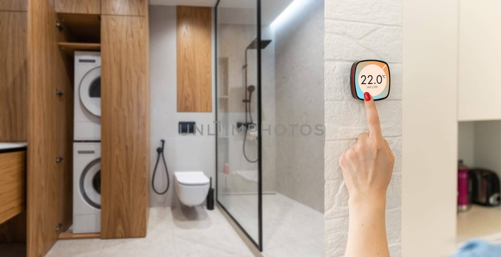 Thermostat indoor smart home in house system for temperature. Winter heating energy efficient automation digital touchscreen wall hand touching device to adjust heating in living room. IoT domotics.