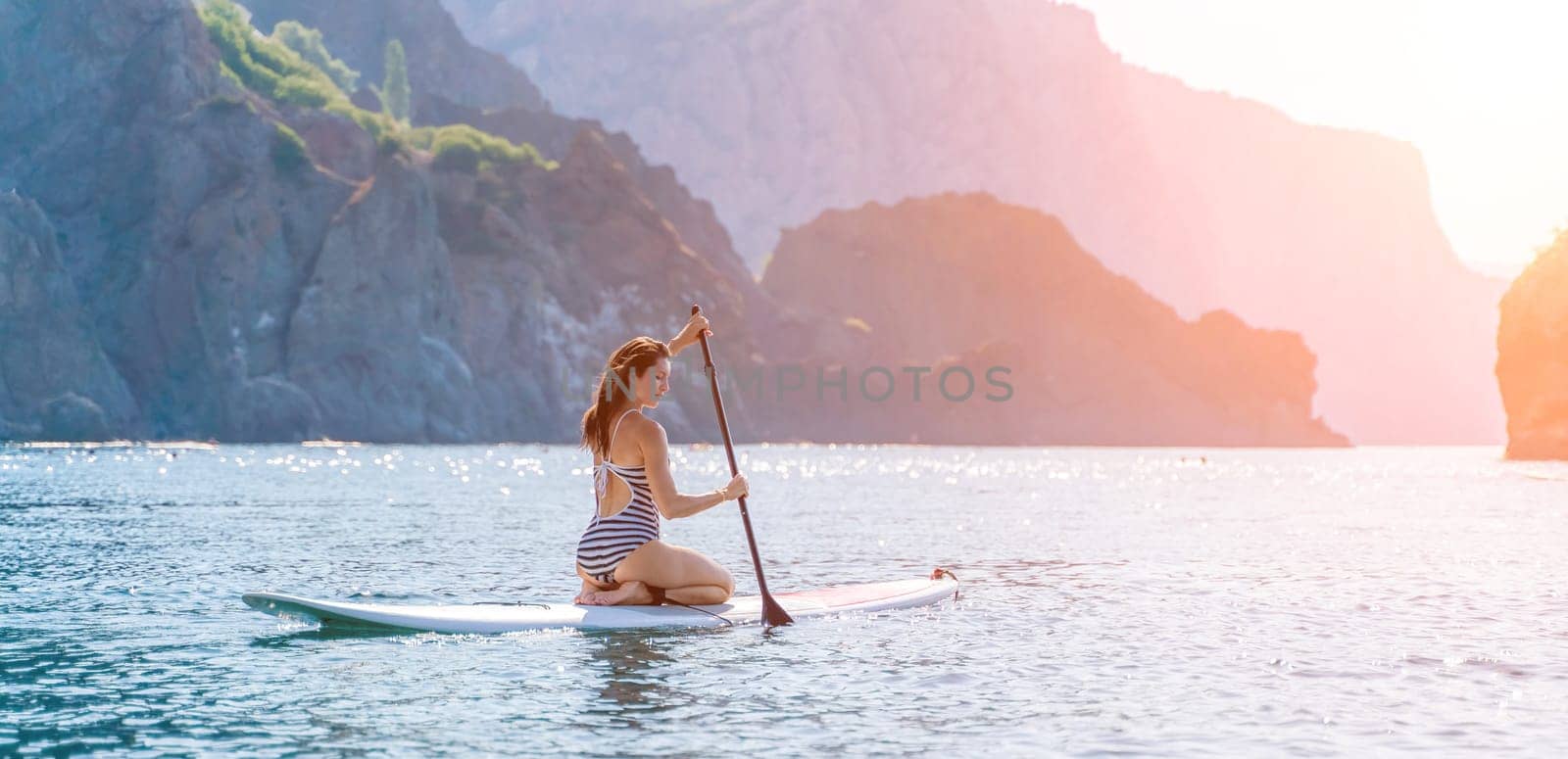 Woman summer surfing on the beach: A sporty girl in a striped swimsuit rides the waves on a surfboard on a sunny summer day at the beach, enjoying the fun and excitement of surfing. by Matiunina