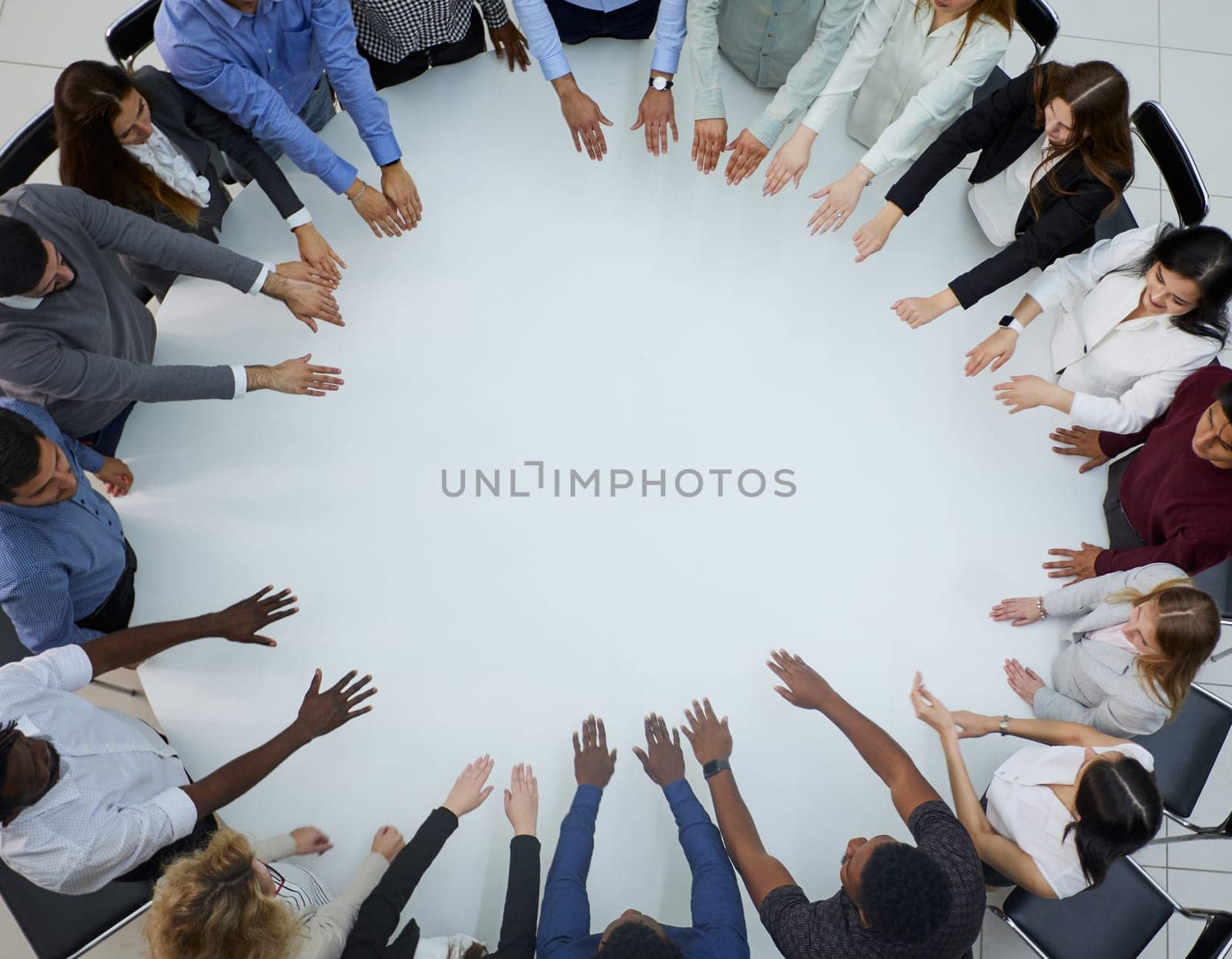 a large group of people sitting at a round table with their arms outstretched by Prosto
