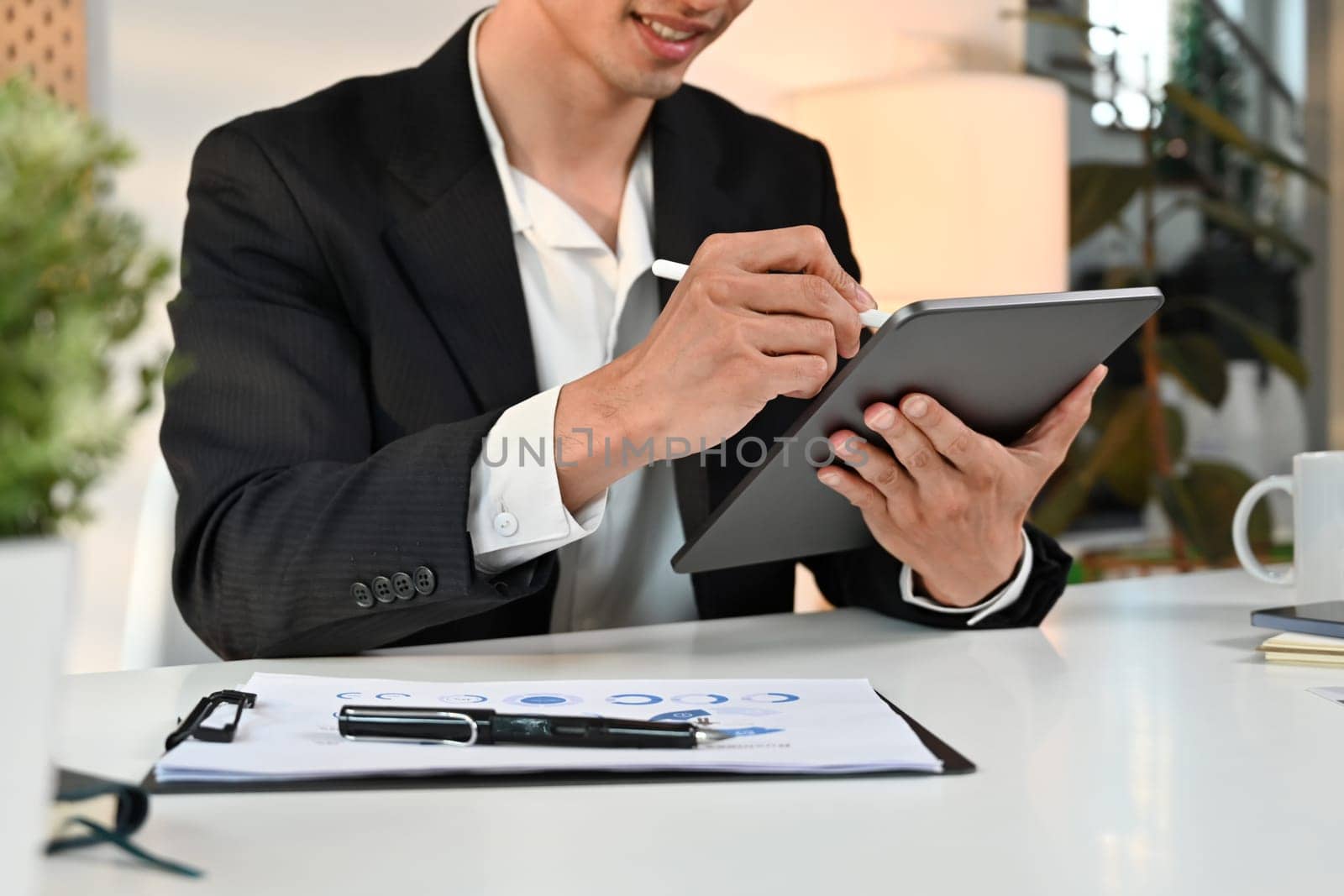 Smiling male entrepreneur analyzing sales statistics management on digital tablet screen by prathanchorruangsak