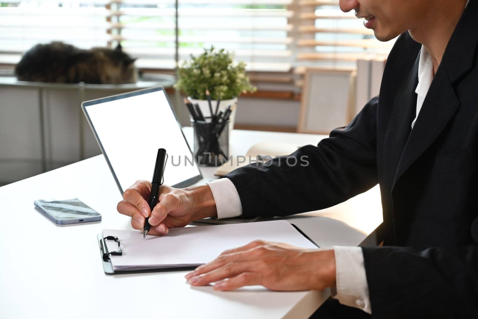 Side view of adult male analyst working bookkeeping documents, signing contracts at office desk by prathanchorruangsak