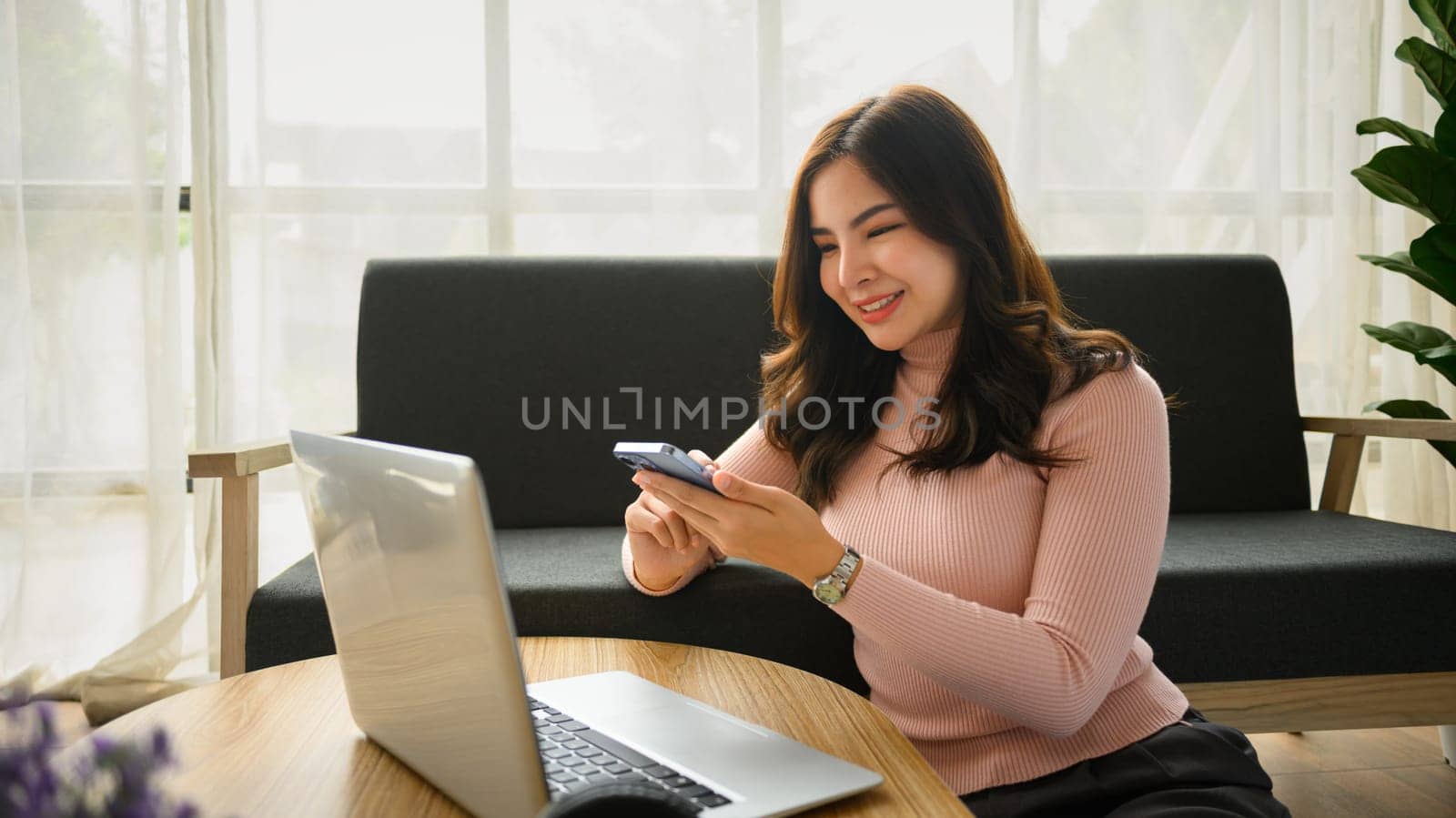 Relaxed young woman using smartphone communication in social media while sitting in living room by prathanchorruangsak