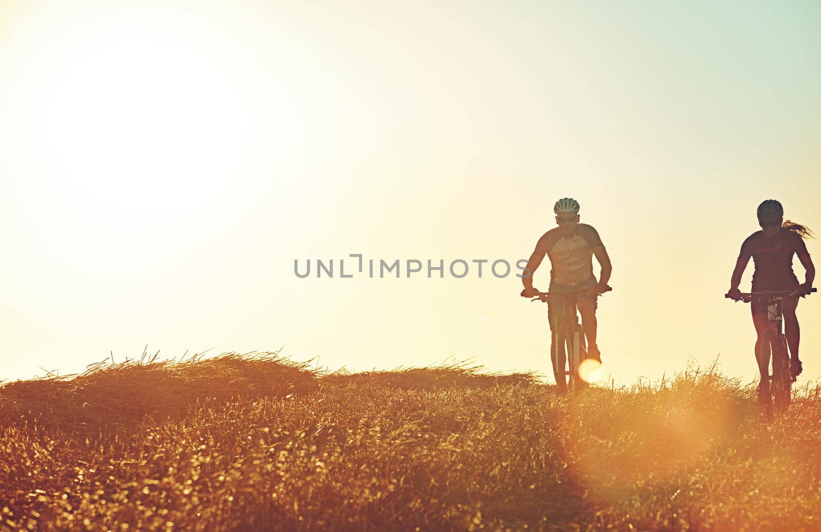 Adventure lies around every corner. a pair of adventurous mountain bikers out on a trail on a sunny day. by YuriArcurs